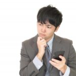スマホを持って考える男性
