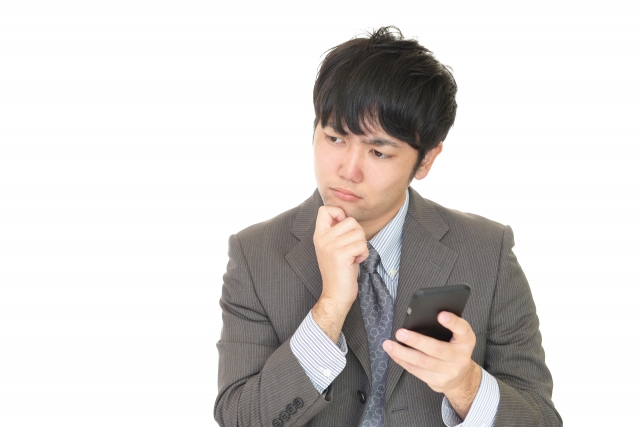 スマホを持って考える男性